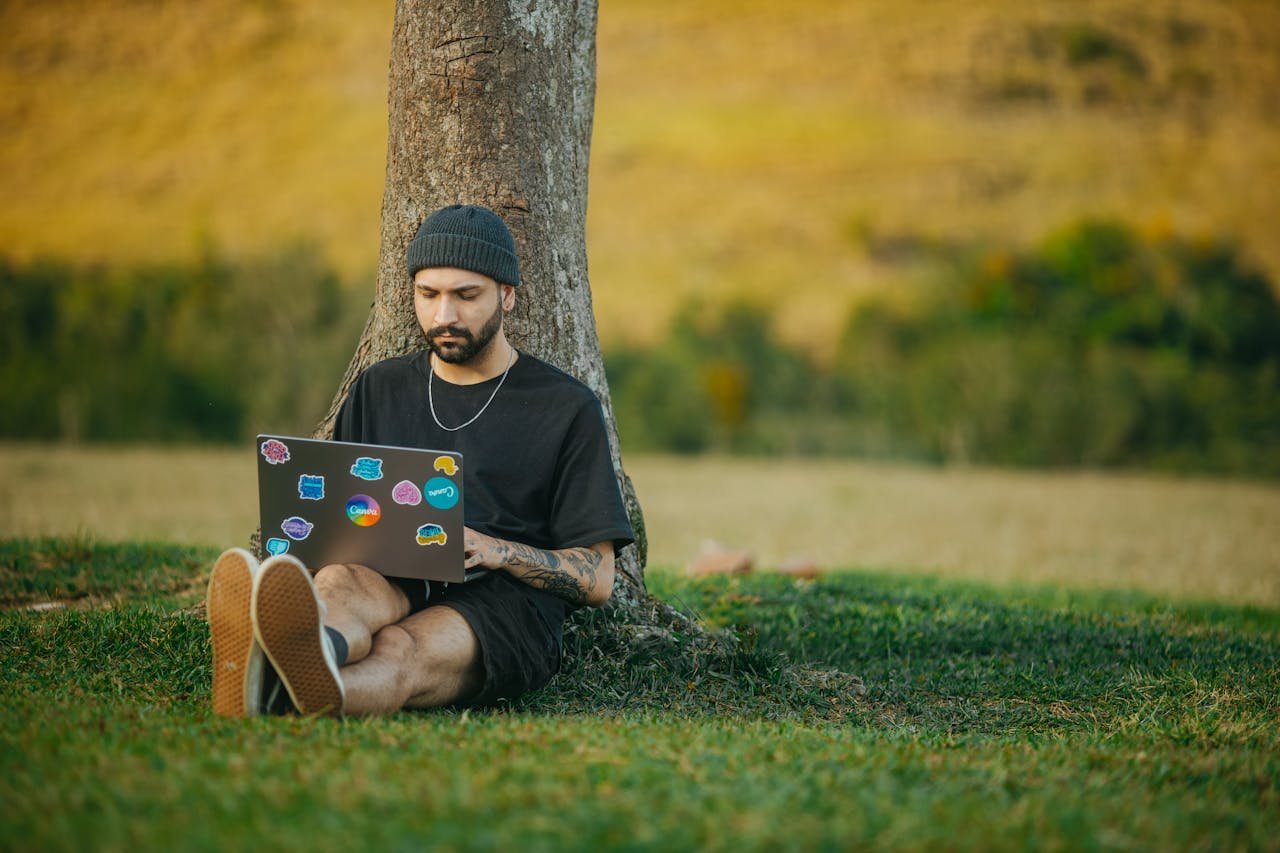 Man with Laptop Leaning on Tree